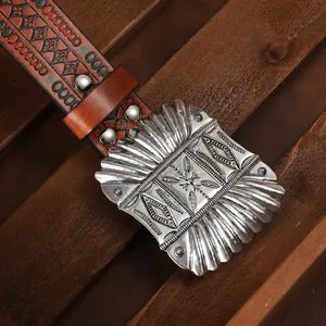 Close-up of western cowboy belt featuring embossed leather and large ornate metal buckle