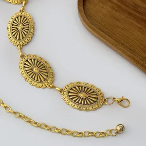 Detailed macro view of vintage gold metal waist chain with embossed oval charms and lobster clasp