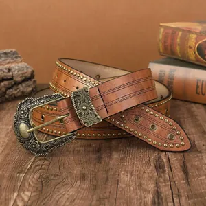 Ceinture vintage en cuir avec boucle florale en bronze et rivets sur fond de bois naturel