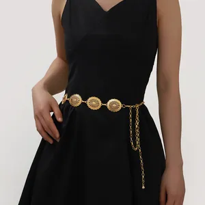 Detail of vintage gold metal waist chain with sunburst motifs on a black dress