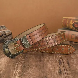 Détail d'une ceinture bohème en cuir clouté avec boucle western à gravures florales