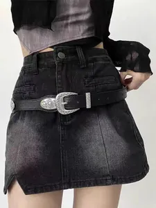 Detailed view of western style black leather belt with ornate silver buckle on denim skirt