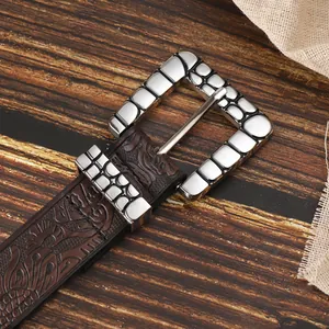 Dettaglio cintura in pelle marrone vintage con fibbia argentata e decori impressi