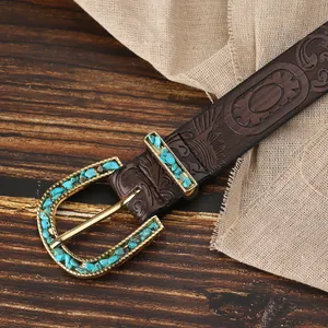 Dettaglio macro della cintura boho con pelle goffrata e fibbia dorata con turchese