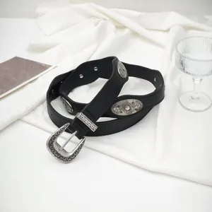 Vintage western black leather belt with ornate silver buckles on white fabric background