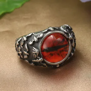 Vue macro d'une bague œil de dragon gothique avec pierre rouge et motifs gravés