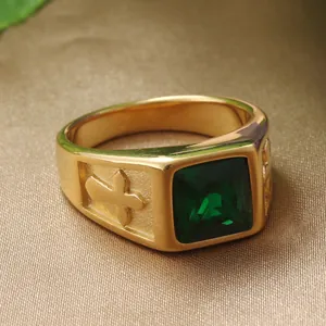 Detail of vintage gold steel ring with square green gemstone and cross relief accents