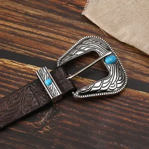 Dettaglio di cintura in pelle boho con goffratura floreale e fibbia turchese