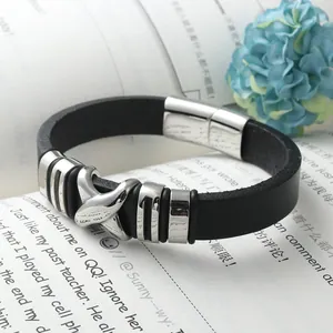 Men's black leather bracelet with stainless steel cross charm on an open book background