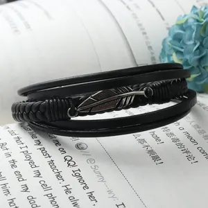 Mehrlagiges geflochtenes schwarzes Lederarmband mit einem detaillierten Federanhänger