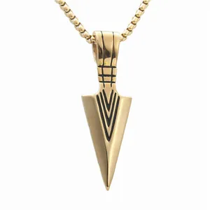 Macro detail of a punk gold spearhead pendant with V-shaped engraving on a box chain