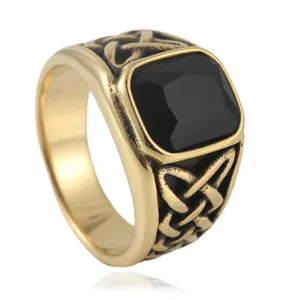 Close-up of vintage gold steel ring with square black gemstone and Celtic knot engraving