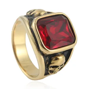 Macro detail of men's gold punk ring with red square stone and skull carvings