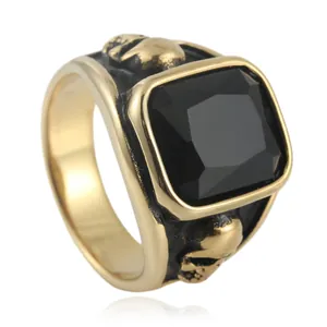Macro detail of gothic gold ring featuring a square black gem and skull side carvings