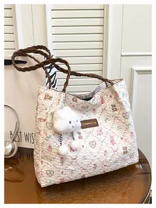 Dettaglio borsa shopper trapuntata con stampa orso, manici intrecciati e ciondolo