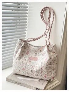 Dettaglio della borsa trapuntata con stampe di orsi e manici rosa intrecciati su libro