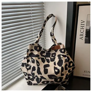 Detail of leopard print canvas tote bag featuring an outer pocket and brown leather tag