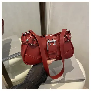 Detail of dark red faux leather crescent bag with silver buckles and metal rivet accents