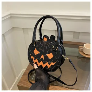 Detail of pumpkin crossbody bag featuring orange face embroidery and spider web stitching