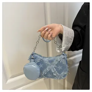 Dettaglio borsa baguette in denim azzurro con stelle sfrangiate e catena d'argento