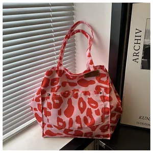 Detailed macro view of red leopard print canvas tote bag with metal rivet pocket detail