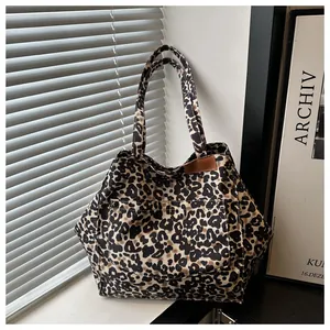 Macro view of leopard print canvas tote bag featuring a stitched front pocket and leather tab