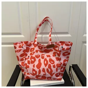 Detailed shot of pink leopard print tote bag with black rivets on front pocket and book