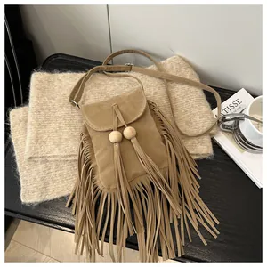 Gros plan détaillé du sac bandoulière marron en suédine avec franges et perles en bois