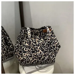 Detail of leopard print canvas tote bag featuring front pocket and leather logo tag
