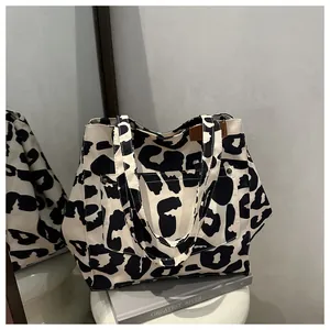 Détail du sac cabas à motif vache avec poche à rivets métalliques et écusson logo