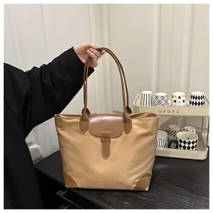 Detailed shot of a khaki Oxford tote bag with brown leather trim and handle for travel