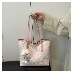 Détail du sac cabas rose avec texture matelassée et broderies de papillons colorés