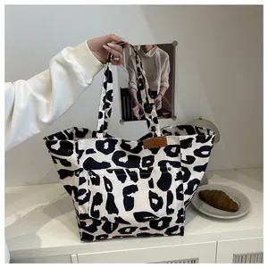Gros plan d'un sac cabas en toile à imprimé léopard noir et blanc avec boutons-pression latéraux