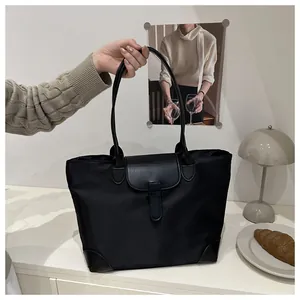 Detail of a large black nylon tote bag with leather trim for daily commuting use