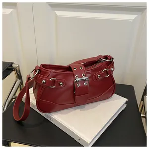 Detail view of deep red crescent shoulder bag with silver studs and metal ring accents
