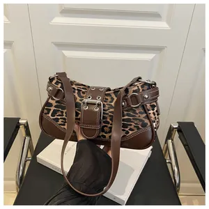 Detail of leopard print crescent bag with leather trim and metal rivets on strap