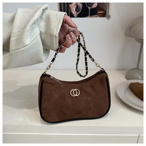 Detail of brown faux suede quilted bag featuring gold metal rings and chain strap