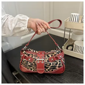 Close-up of leopard print baguette bag with red leather trim and silver studs