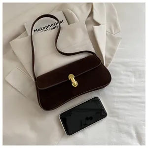 Detail of suede underarm bag with gold lock and smartphone for size reference