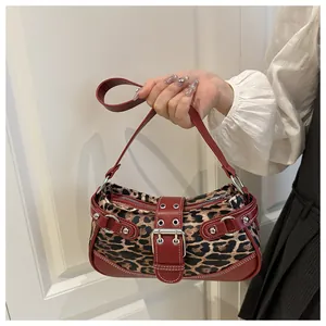 Close-up of leopard print crescent bag with red leather trim and silver rivet details
