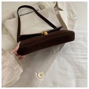Detail of vintage dark brown suede underarm bag with gold metal clasp on a blazer