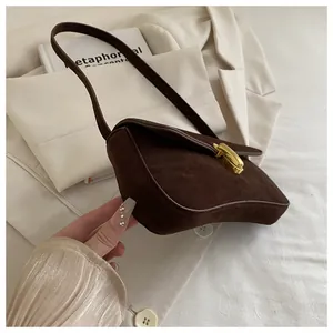 Detail shot of vintage brown suede underarm bag with elegant gold metal buckle hardware