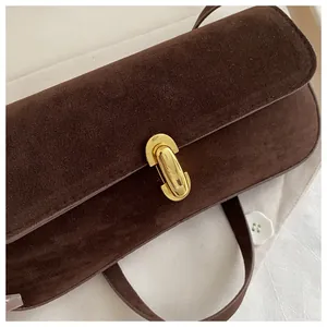 Close-up of dark brown suede shoulder bag with polished gold oval metal clasp detail