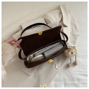 Deep brown matte underarm bag showing interior space with phone and makeup items