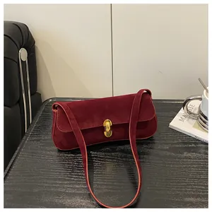 Detailed close-up of matte burgundy underarm bag with a golden horseshoe clasp and strap