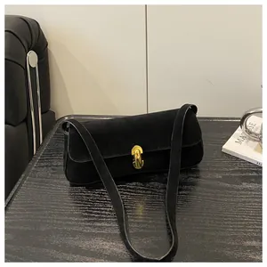 Close-up of golden metal clasp on black matte suede shoulder bag with retro finish