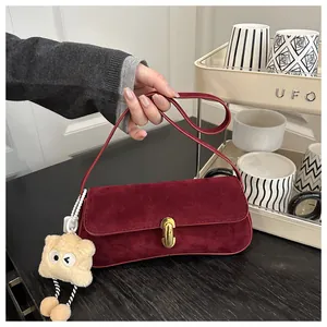 Close-up of burgundy frosted suede shoulder bag with gold clasp and plush star charm