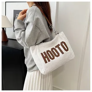 Detalle del bolso tote de felpa blanca con bordado HOOTO y correa de cuero y cadena