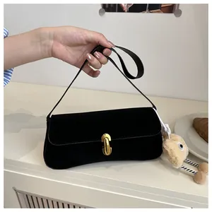 Detail of a black suede underarm bag featuring a gold oval clasp and cute plush charm