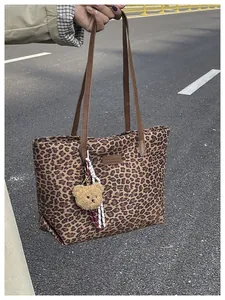Dettaglio della borsa tote leopardata con manici marroni e un portachiavi a forma di orso